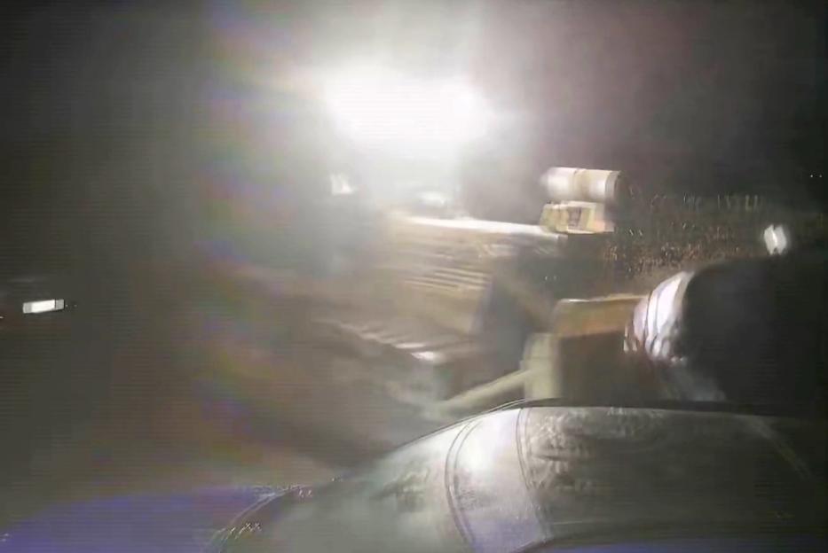 A blurry night-time photo of a bulldozer ramming into the porch of a pub.