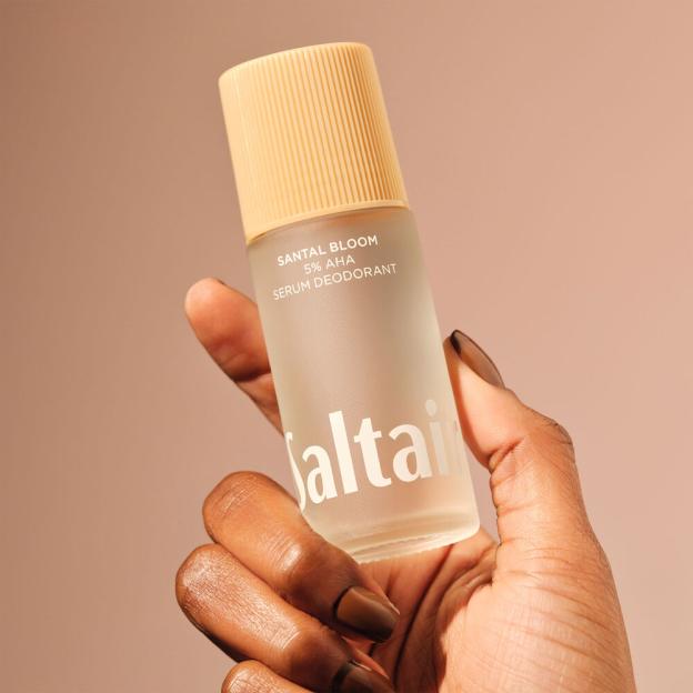 Hand holding a Santal Bloom 5% AHA Serum Deodorant bottle.