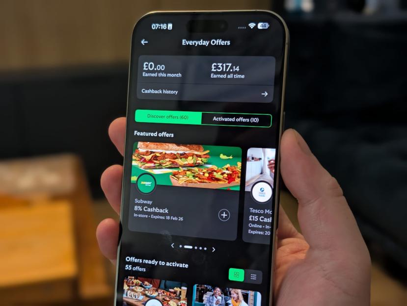 A person holding a phone displaying an "Everyday Offers" app screen with "£0.00 Earned this month" and "£317.14 Earned all time", and a Subway 8% cashback offer.