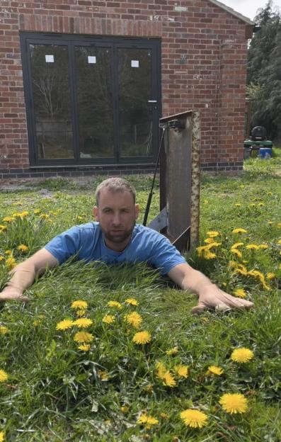 Dave Billings climbing out of a bunker hatch in his garden.