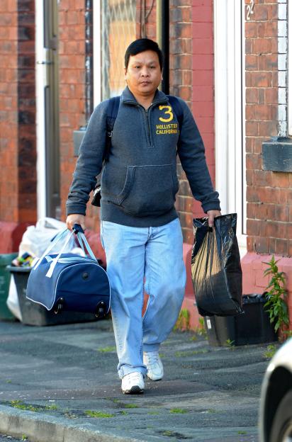 Victorino Chua, a nurse found guilty of murder and GBH, walking on a street carrying bags.