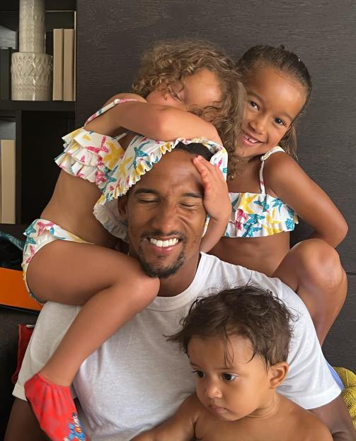 Scott Sinclair smiling with two young girls in swimsuits and a baby.
