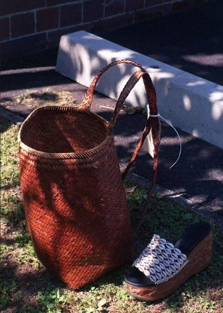 a wicker basket sits next to a sandal with shells on it