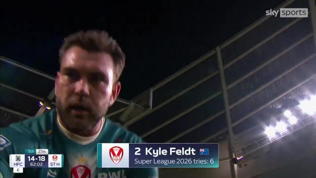 A rugby player looking into a camera held by a camera operator who has just fallen, with game scores and player stats visible on screen.
