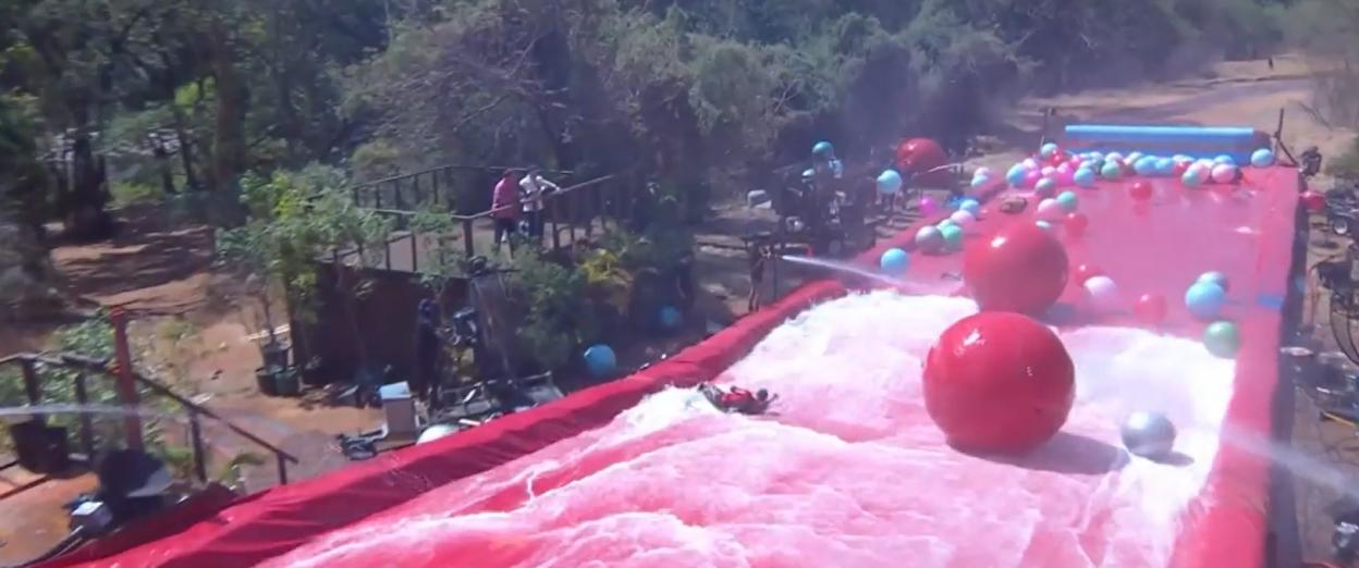 An outdoor obstacle course with a red-colored, foam-filled slide and giant red, blue, and green balls.