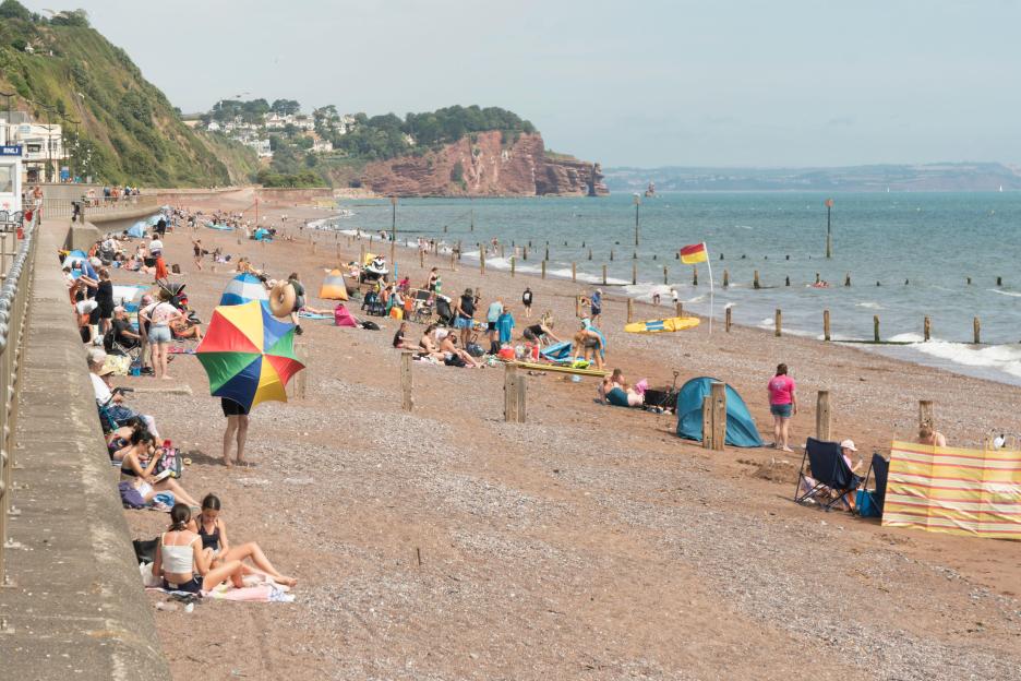 People enjoying summer sunshine on the beach at Teignmouth in Devon, England.
