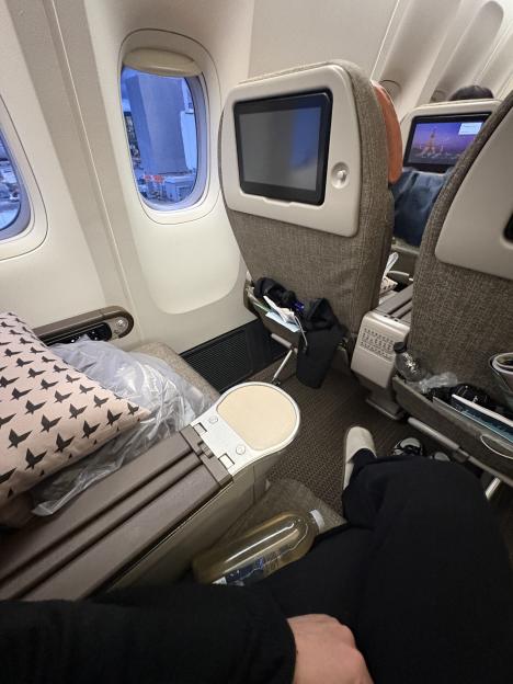 View from an airplane window seat, with personal items visible.