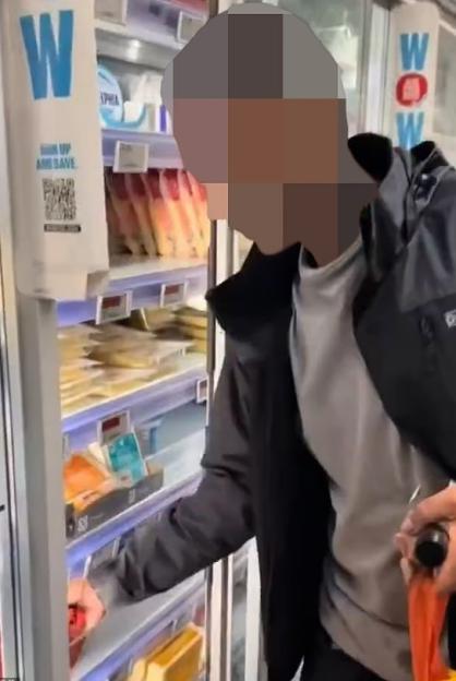 A person selecting an item from a refrigerated display case in a store.