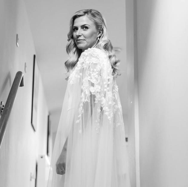 Black and white portrait of Georgie Campbell looking over her shoulder in a white lace and tulle dress.