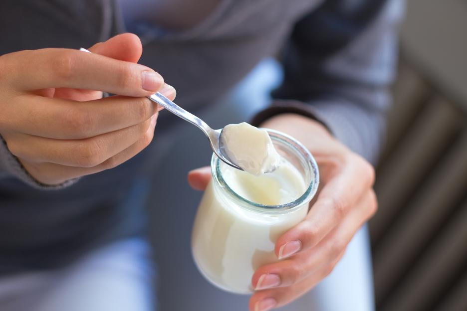 Woman eating yogurt with a spoon.