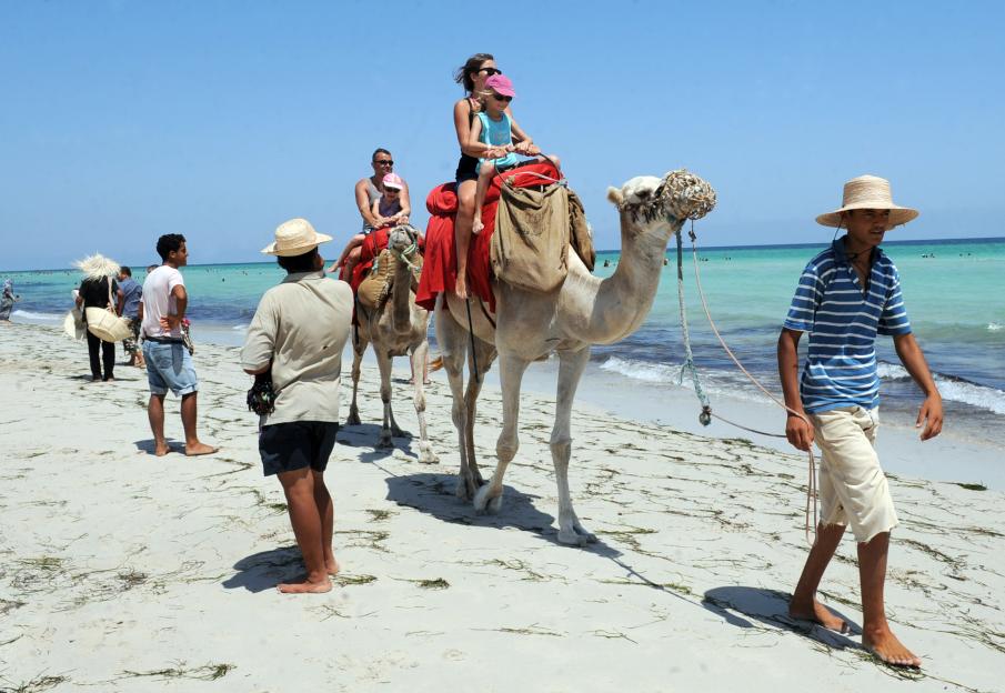 Tourists enjoy a camel ride on the pink
