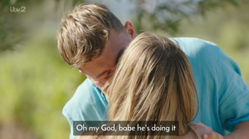 A man and woman embracing, with subtitles reading, "Oh my God, babe he's doing it."