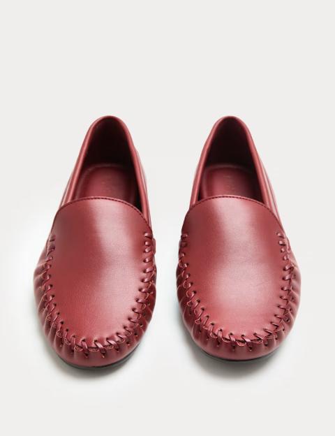 A pair of red slip-on loafers with whipstitch detail.