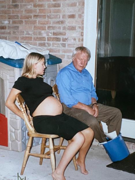 A pregnant woman and an older man sitting in chairs.