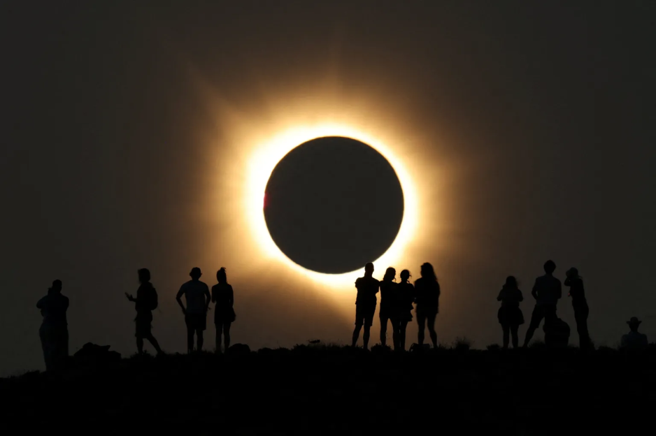 Silhouettes of people watching a total solar eclipse.