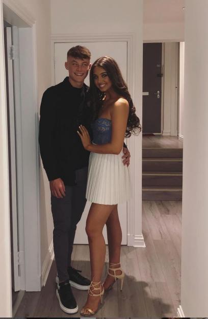 A man and a woman posing together in a hallway.