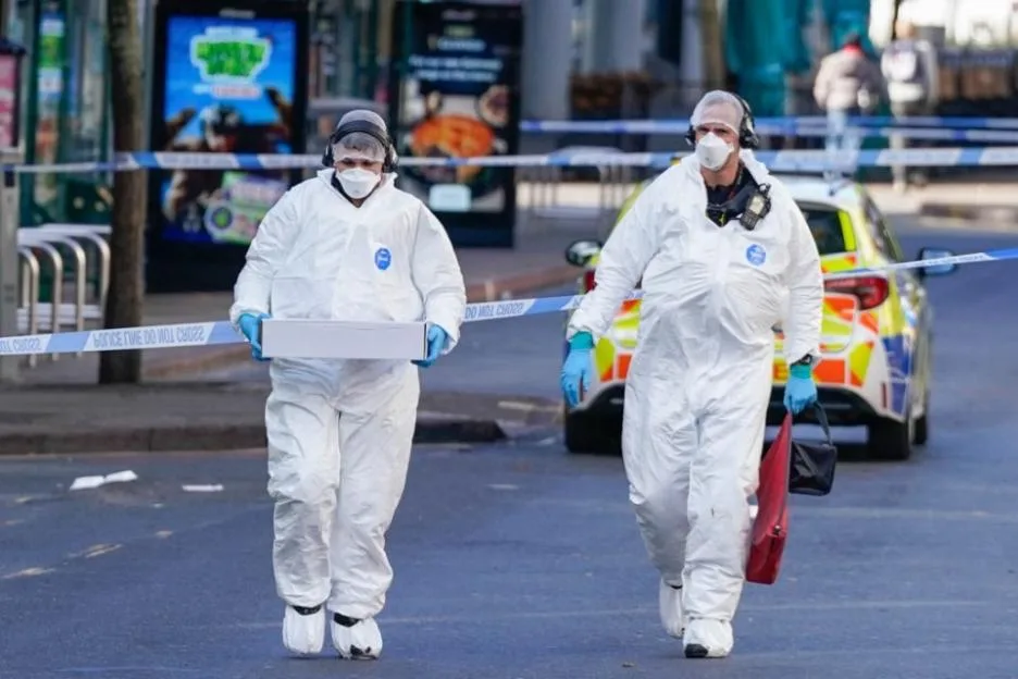 Forensic investigators in protective suits examine the scene after a police officer was shot in Nottingham.