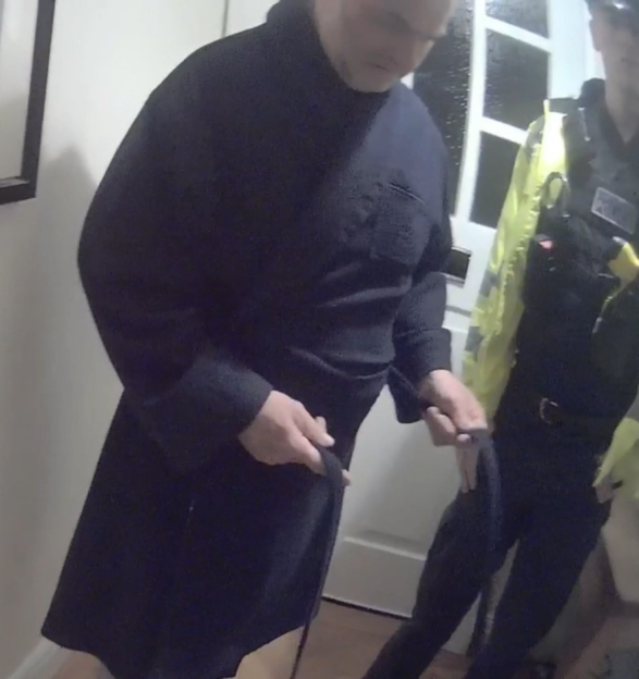 A man in a navy shirt and kilt-like garment standing near a police officer.