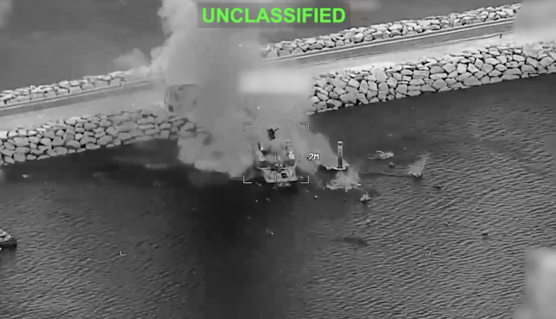 Thermal image of a burning boat with smoke visible from an aerial view.