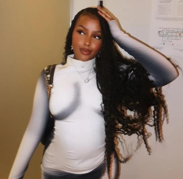 A young woman with long, braided hair poses, looking to her right, wearing a tight, long-sleeved turtleneck shirt.