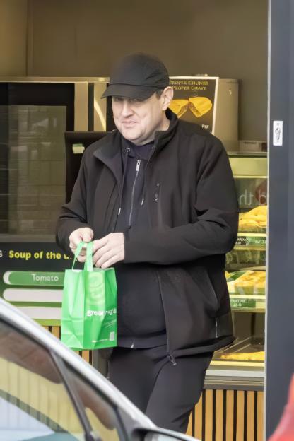 Peter Kay holding a green Greggs bag.