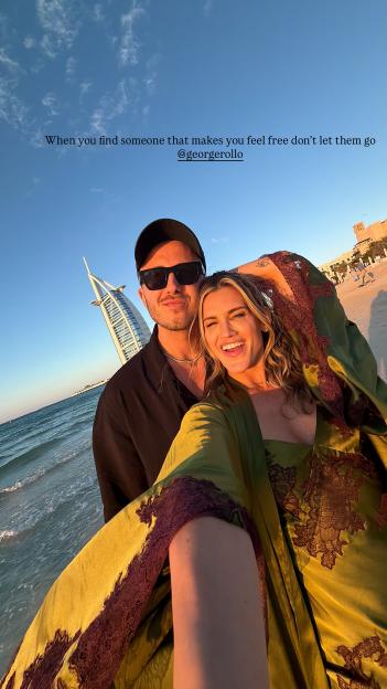 Ashley Roberts and George Rollo smiling on a Dubai beach with the Burj Al Arab hotel in the background.