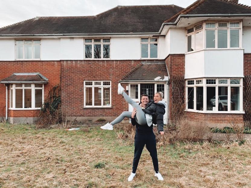 Billie Faiers and her partner posing in front of their home undergoing renovation.