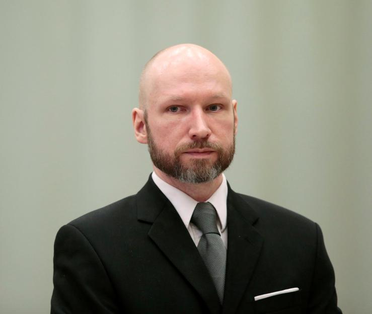 A man with a bald head and beard, wearing a suit and tie, looks directly at the camera.