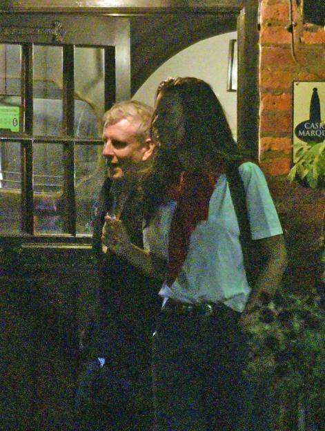 TV presenter Patrick Kielty smiles while leaving a pub with a tall brunette.