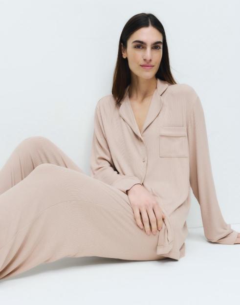 A woman sitting on the floor wearing a fawn ribbed pyjama set.