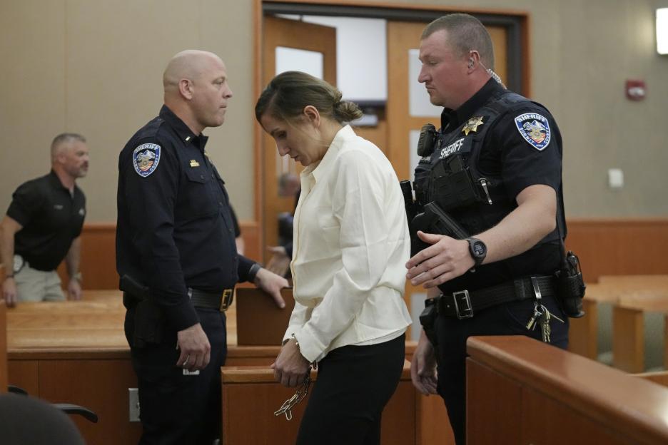 Kouri Richins, handcuffed, escorted by two police officers in a courtroom.