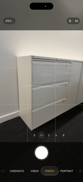 iPhone camera interface displaying a filing cabinet, with a "1x" zoom setting highlighted.