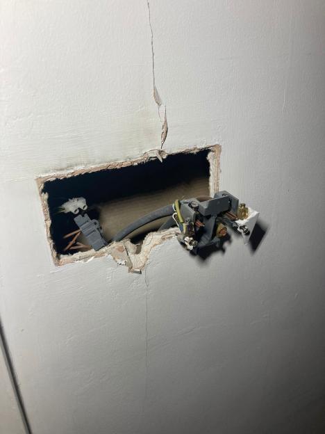 Lightning damage to a wall, showing exposed electrical wires and a cracked surface.