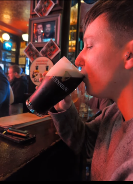 Person taking a sip of Guinness beer in a pub.