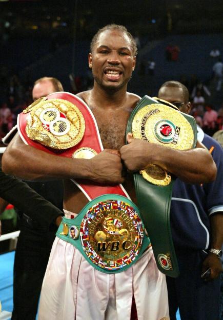 Lennox Lewis celebrates his heavyweight championship victory with three championship belts.