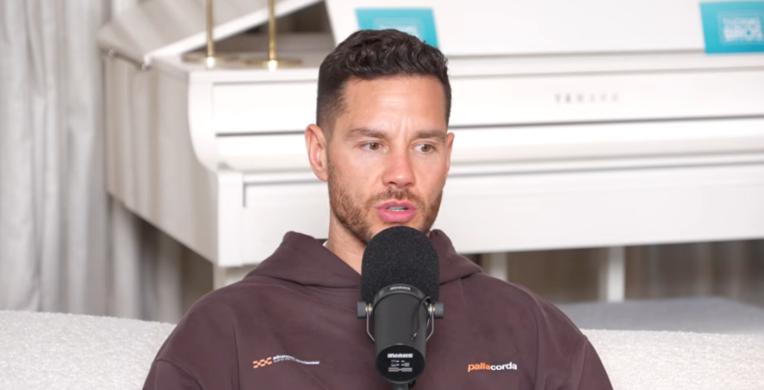 A man with a microphone in front of him, speaking.