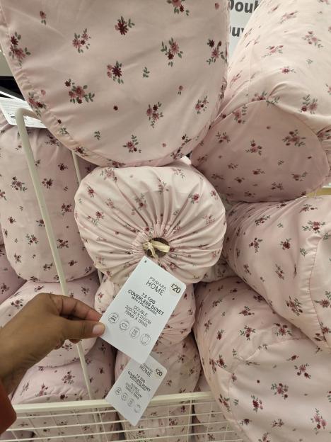 A person's hand holding a label for a pink floral duvet and pillowcases.