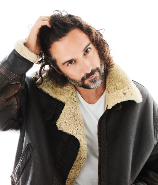 Man with curly hair and beard in a sheepskin jacket.