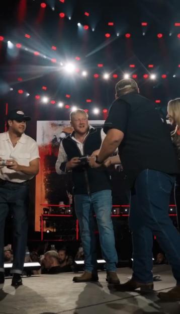 Kaleb Cooper and Luke Combs on stage, shotgunning cans of lager.