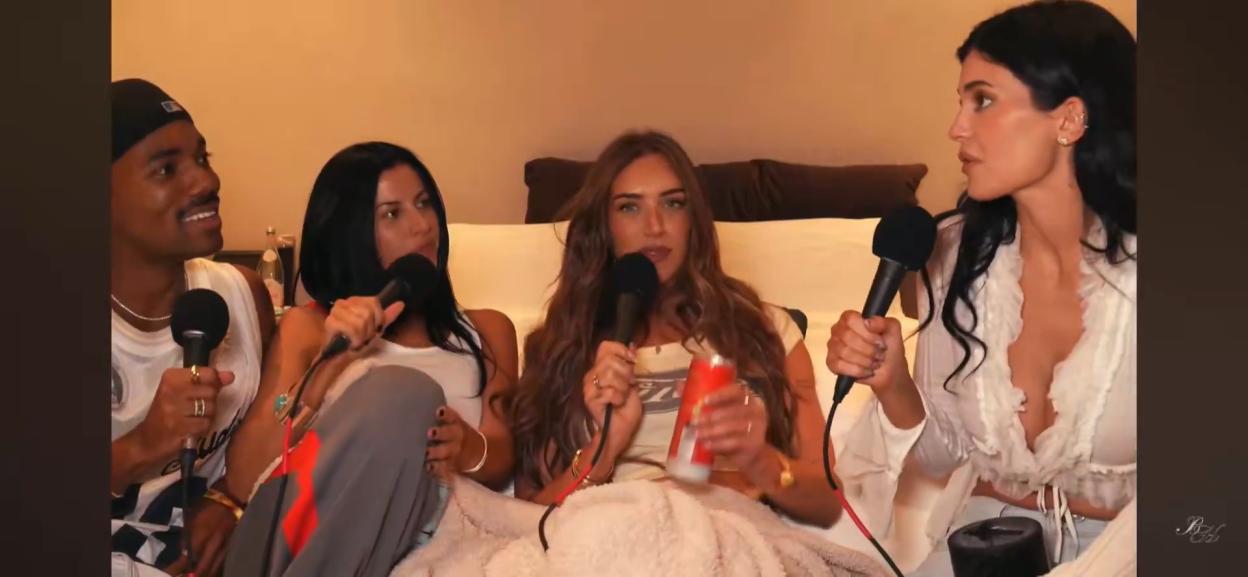 Four people, two men and two women, seated on a couch holding microphones, likely for a podcast.