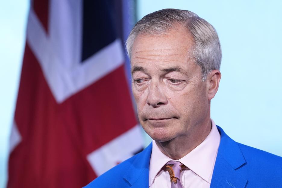 Nigel Farage, leader of Reform UK, stands before a Union Jack flag.