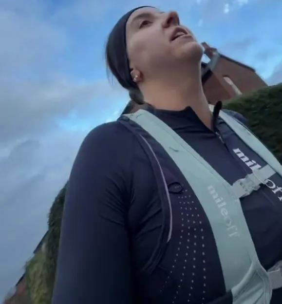 Woman running in a black top and a mint green running vest.