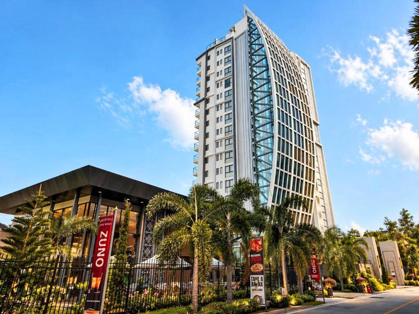 The Elysium Prațumnak Pattaya hotel building and a connected shorter building surrounded by palm trees.