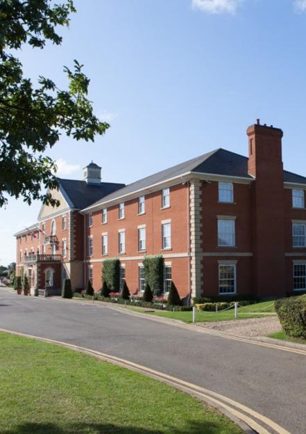 A large red brick building with white window frames and a chimney at Towcester, Silverstone.