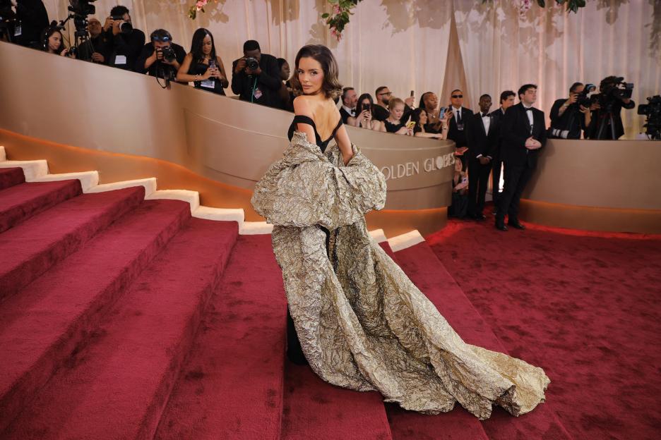 Maura Higgins poses on the red carpet at the Golden Globes in a black and gold ruffled gown.