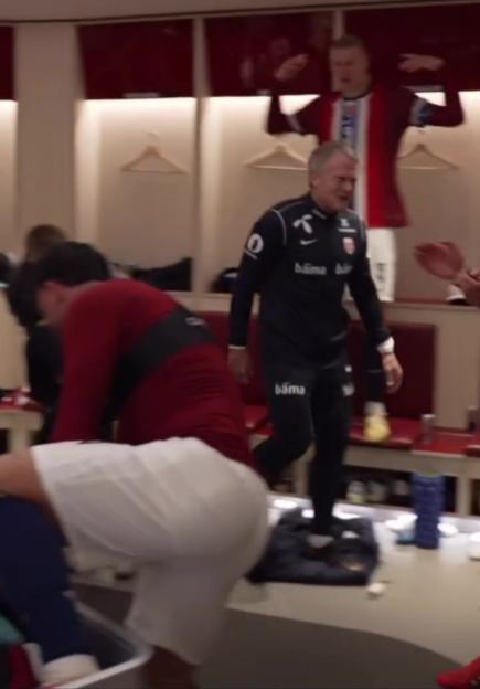 Three men in a locker room, one is jumping and two are walking.