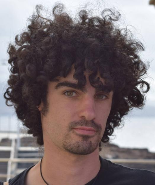 Jorge Javier Martin Carreno, a man with curly dark hair, light-colored eyes, and a beard, looks directly at the camera.