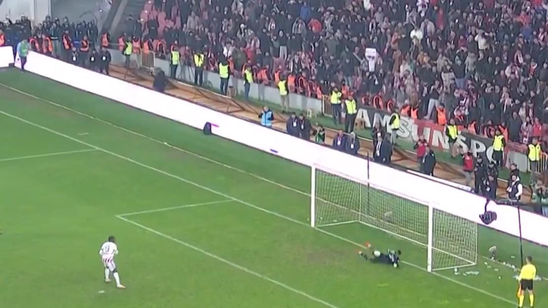 A football player dives to save a goal while another player watches.