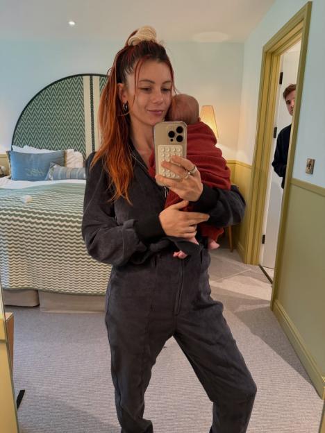 Dianne Buswell taking a mirror selfie holding a baby.