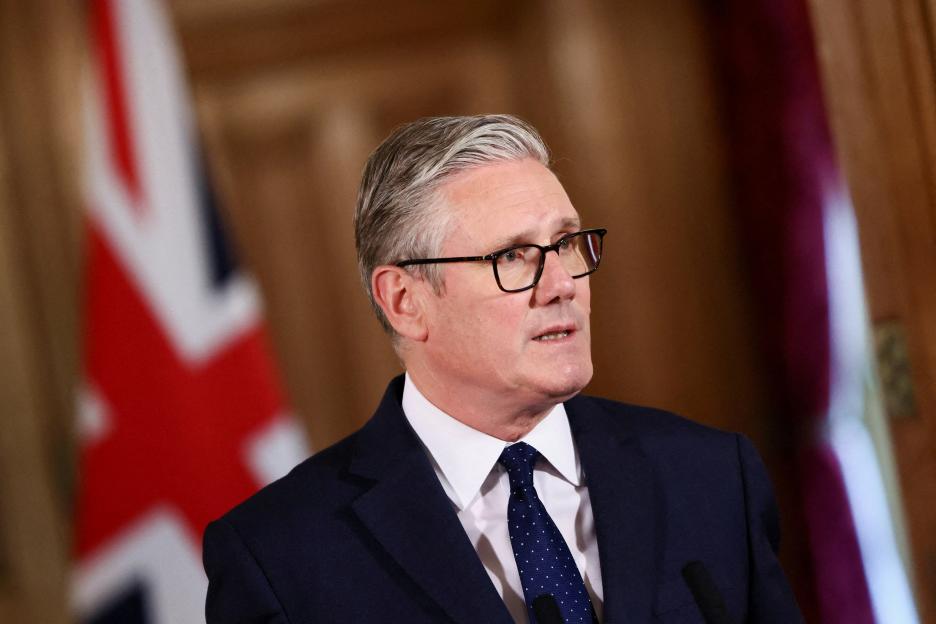 British Prime Minister Keir Starmer speaking at a media event, with the Union Flag visible behind him.